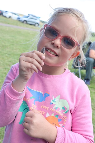 A young girl holds up a belemnite fossil 